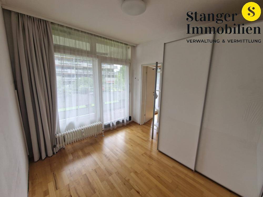 Schlafzimmer mit Holzboden, großen Fenstern und integrierten Schränken für optimalen Stauraum.