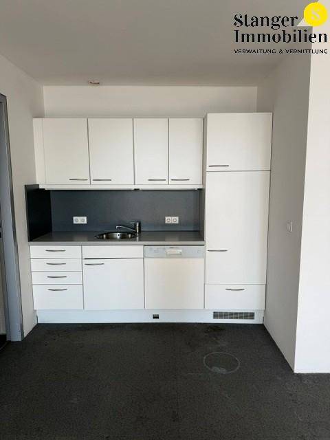 Moderne Küchenzeile mit weißen Schränken, Spüle und integriertem Geschirrspüler in einem Büroraum.