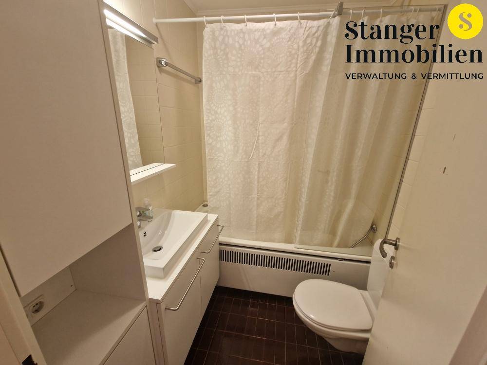 Funktionales Badezimmer mit Badewanne, WC und modernem Waschtisch, ausgestattet mit Duschvorhang.