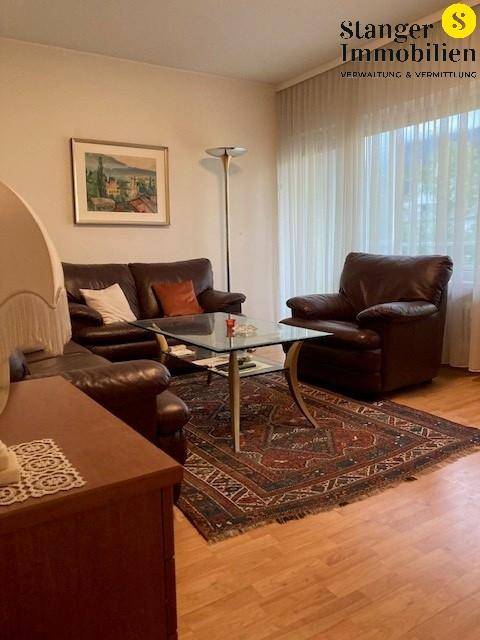 Wohnzimmer mit bequemen Ledersofas, Holzboden und großen Fenstern für viel Tageslicht.