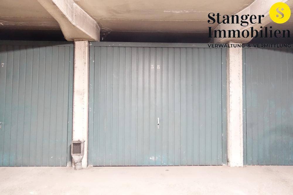 Geschlossene Garagentore in einer Tiefgarage, umgeben von Betonpfeilern und grauen Wänden.