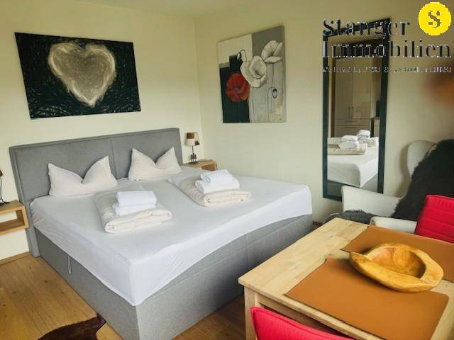 Helles Schlafzimmer mit Doppelbett, kleinem Esstisch und einem großen Spiegel, der den Raum erweitert.