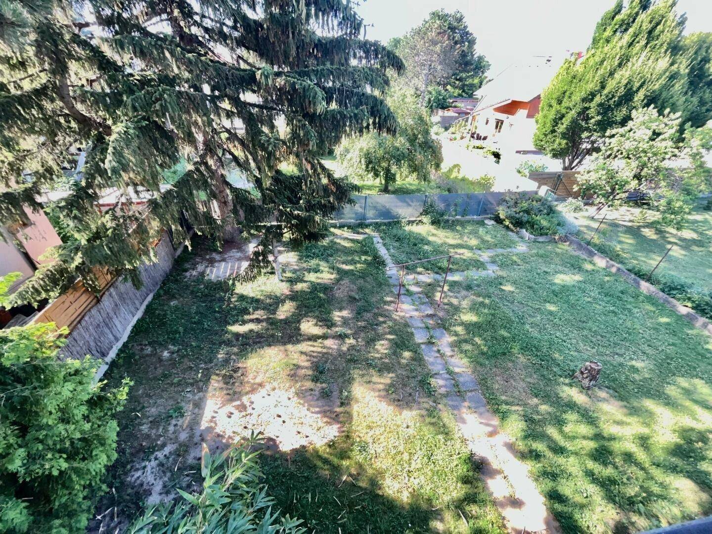 Weitläufiger Gartenbereich von oben betrachtet, mit Rasenfläche und Baumbestand.