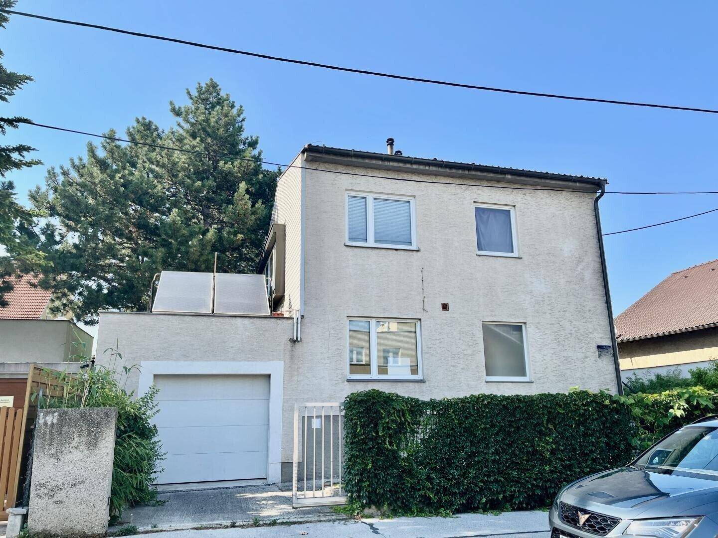 Vorderansicht des Hauses mit integrierter Garage und gepflegter Hecke im Vorgarten.