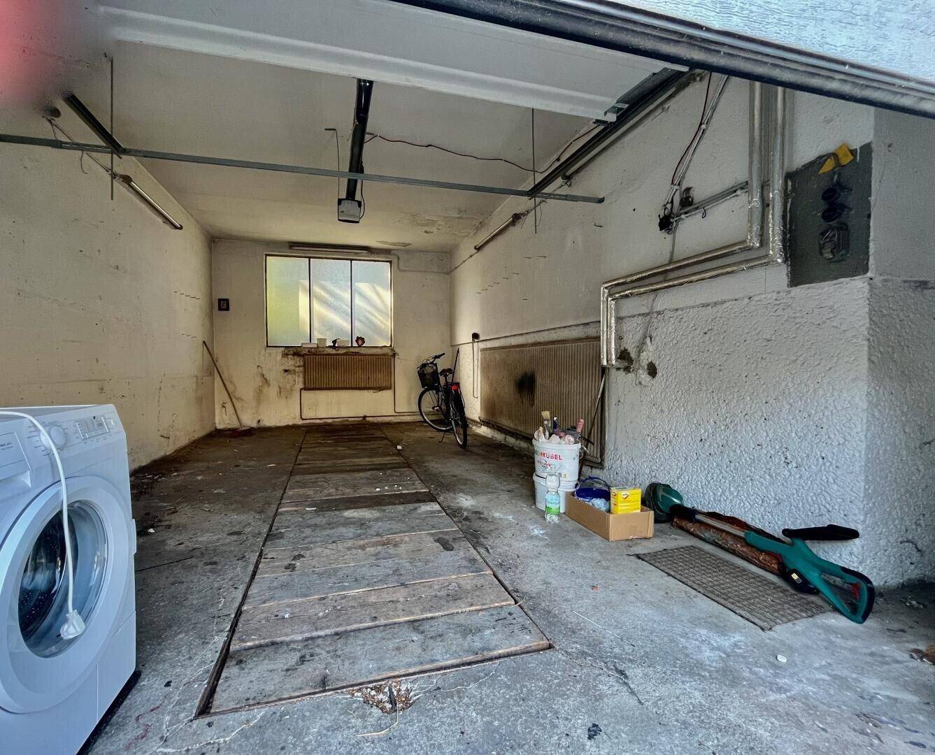Geräumige Garage mit Waschmaschine, Fenster und viel Platz für Fahrzeuge und Lagerung.