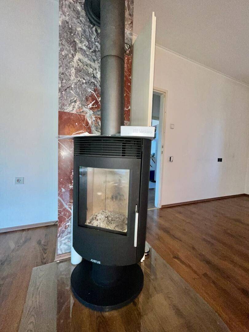 Moderner Holzofen mit Marmorverkleidung im Wohnzimmer, sorgt für gemütliche Wärme.
