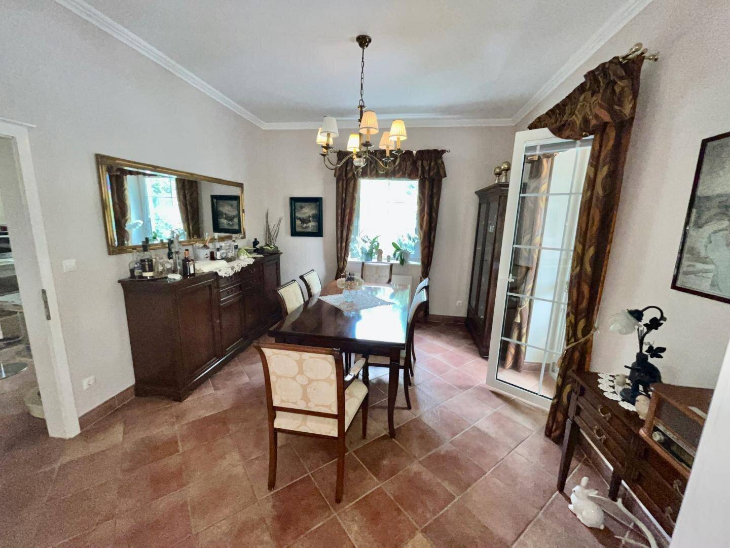 Klassisches Esszimmer mit großem Holztisch, passenden Stühlen und Terrakotta-Fliesenboden.