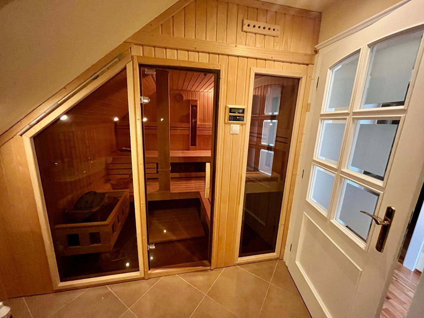 Moderne Sauna im Dachgeschoss mit Holztäfelung und Glastüren für Entspannung.