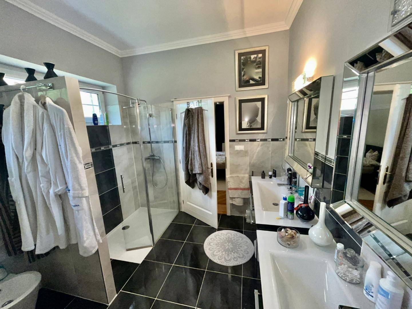 Modernes Badezimmer mit Doppelwaschbecken, großer Duschkabine und dunklen Bodenfliesen.