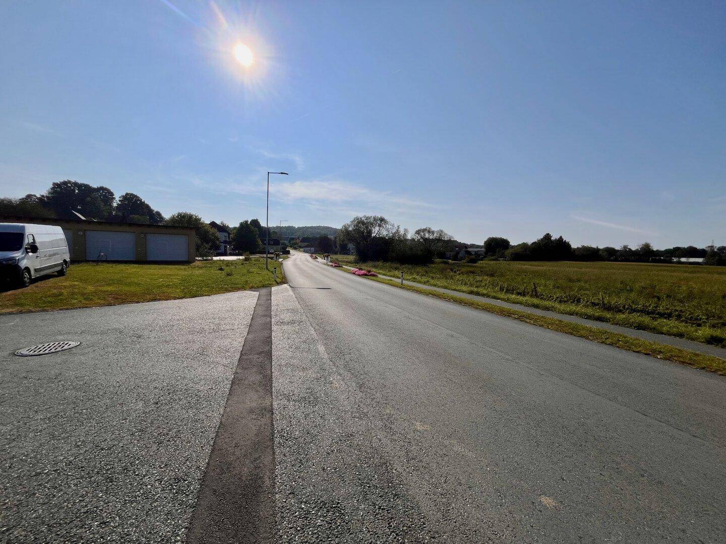 Sonnige Landstraße mit Parkplatz und weitem Blick auf die umliegende Landschaft.