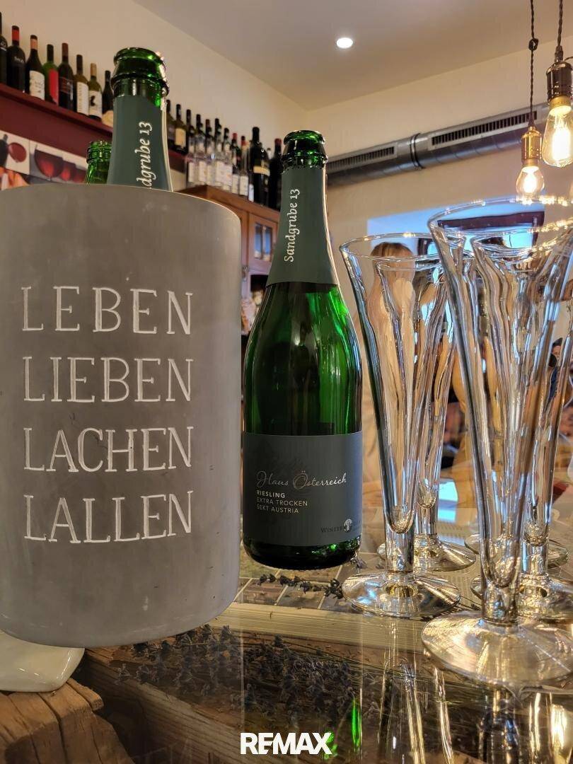 Sektflaschen in einem Kühler mit Aufschrift und eleganten Sektgläsern, bereit für einen Empfang.