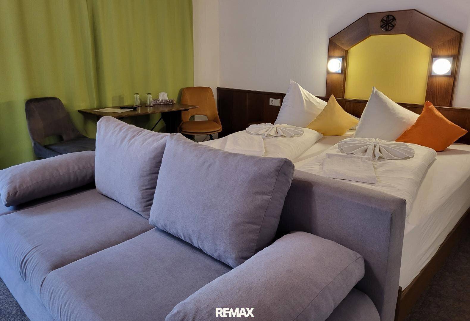 Gemütliches Schlafzimmer mit Doppelbett, Sofa und einem kleinen Schreibtisch, ideal für Gäste.