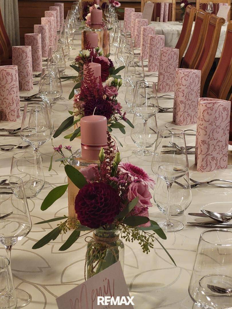 Festlich gedeckter Esstisch mit eleganten Blumenarrangements und Kerzen für eine besondere Feier.