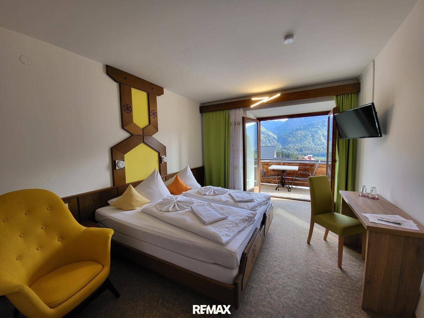 Geräumiges Schlafzimmer mit Doppelbett und Zugang zu einem Balkon mit atemberaubendem Bergblick.