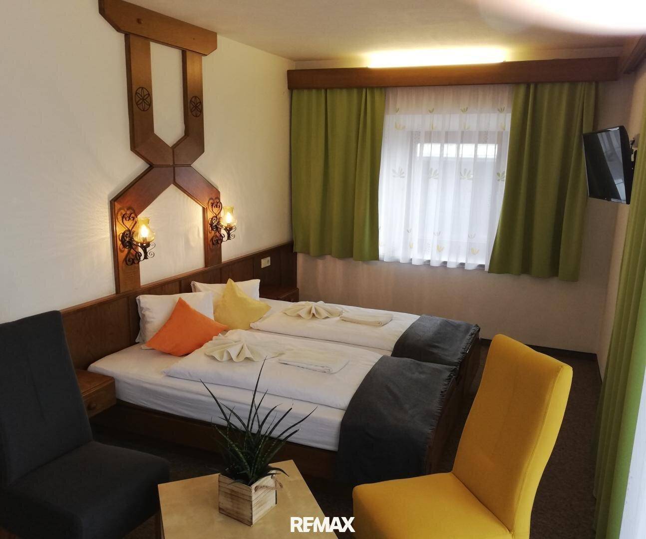 Komfortables Schlafzimmer mit Doppelbett, zwei Stühlen und einer dekorativen Pflanze.
