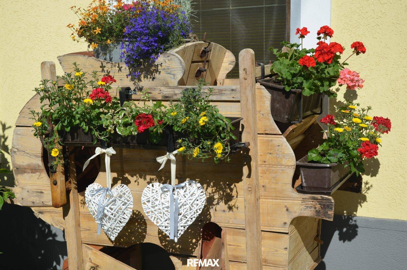 Rustikale Außendekoration mit bunten Blumen in Holzkästen, die eine einladende Atmosphäre schaffen.