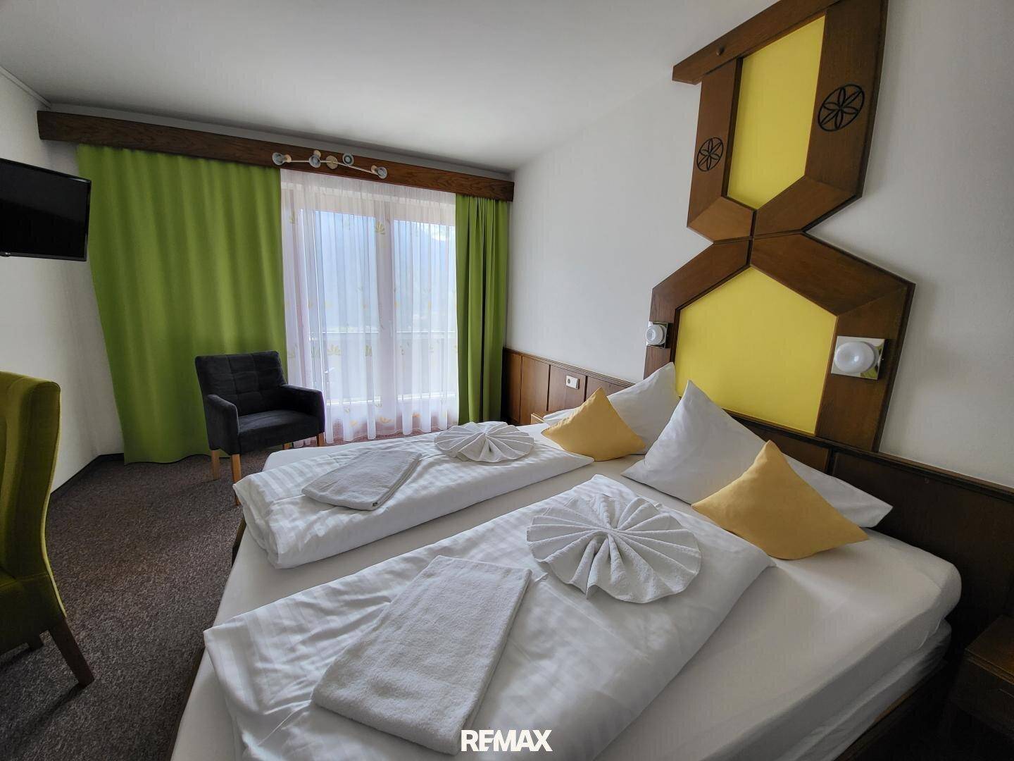 Helles Schlafzimmer mit Doppelbett und einem Fenster, das viel Tageslicht hereinlässt.