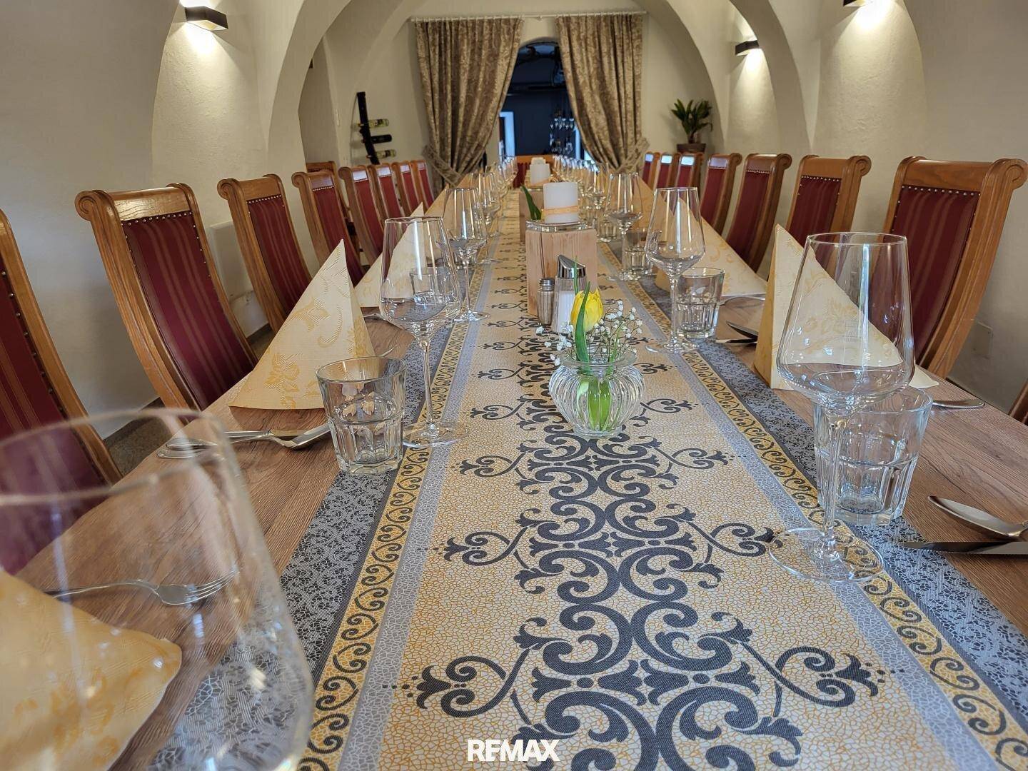 Langer, festlich gedeckter Esstisch mit eleganten Stühlen in einem Raum mit Gewölbedecken.