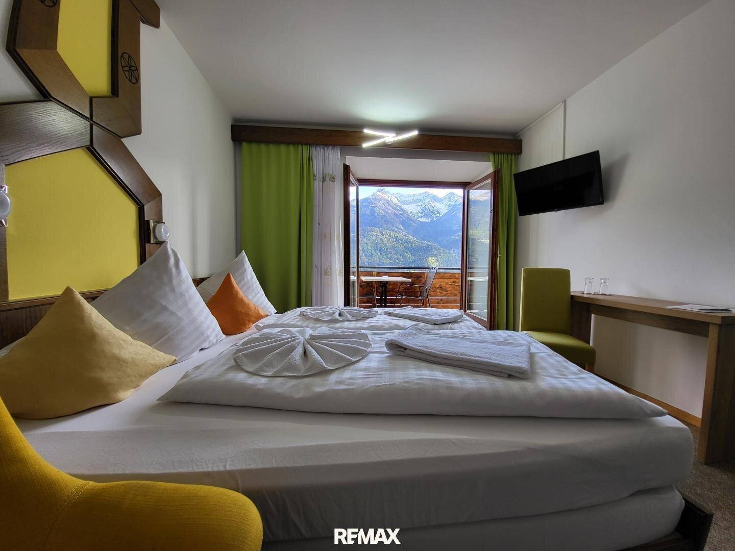 Helles Schlafzimmer mit Doppelbett und direktem Zugang zu einem Balkon mit spektakulärem Bergblick.