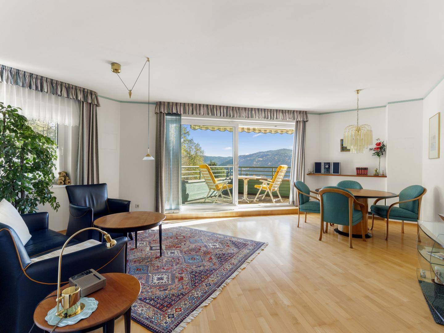 Heller Wohn- und Essbereich mit Parkettboden, Zugang zum Balkon und Bergblick.