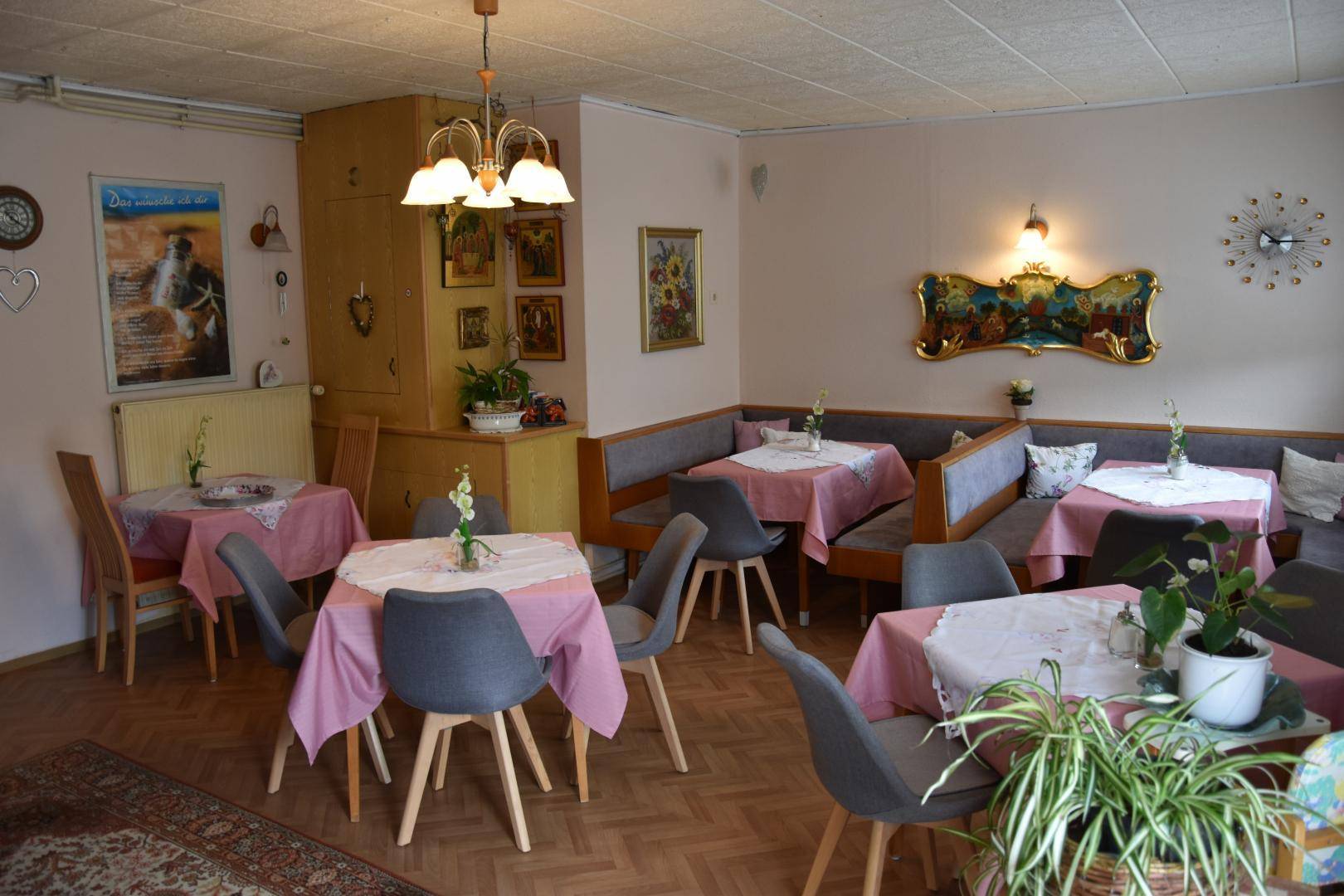 Gemütlicher Speisesaal mit traditioneller Einrichtung, mehreren Tischen und floralen Dekorationen, hell und freundlich.