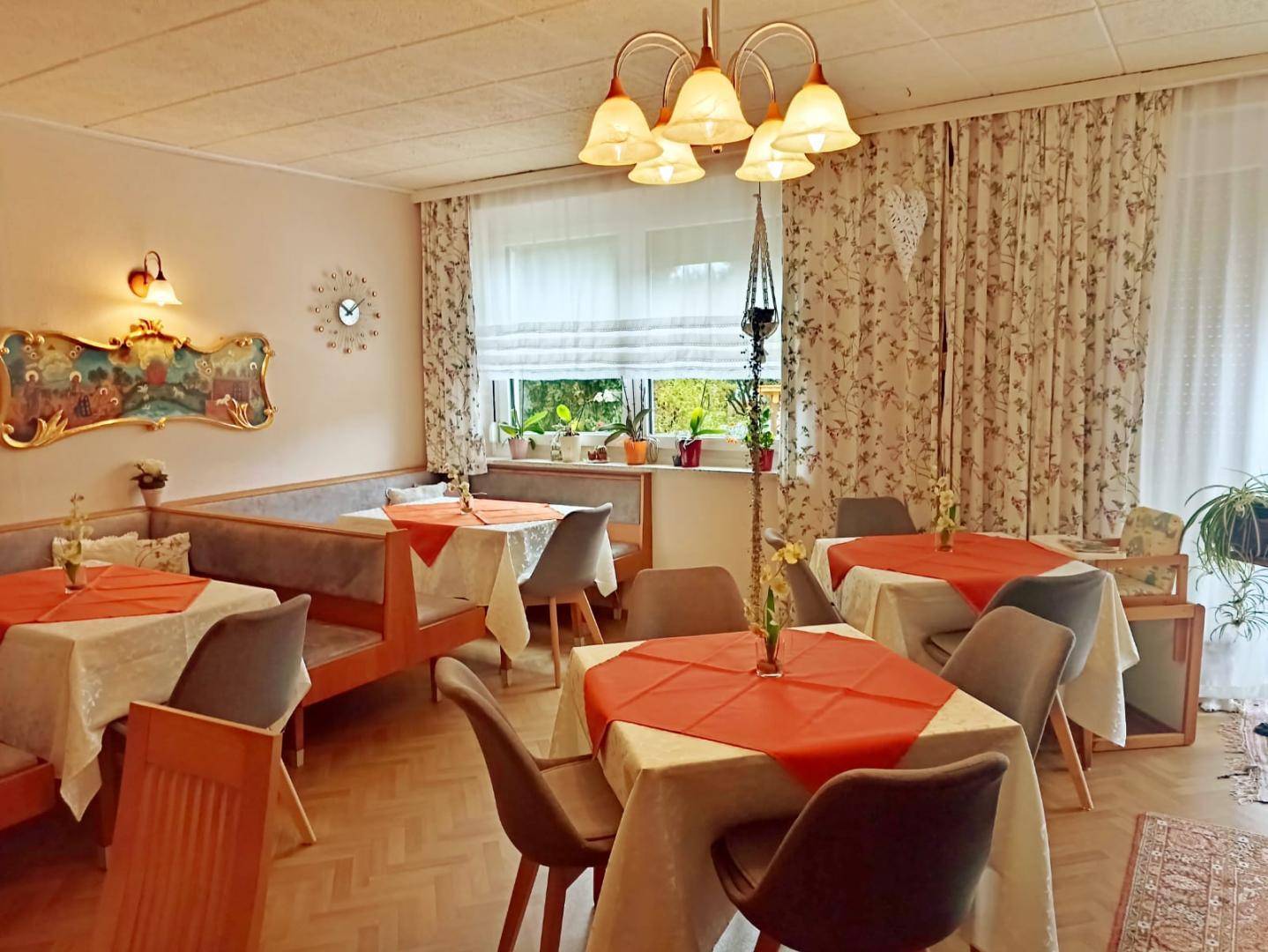 Einladender Speisesaal mit mehreren Tischen, bequemen Sitzbänken und großen Fenstern für viel Licht.