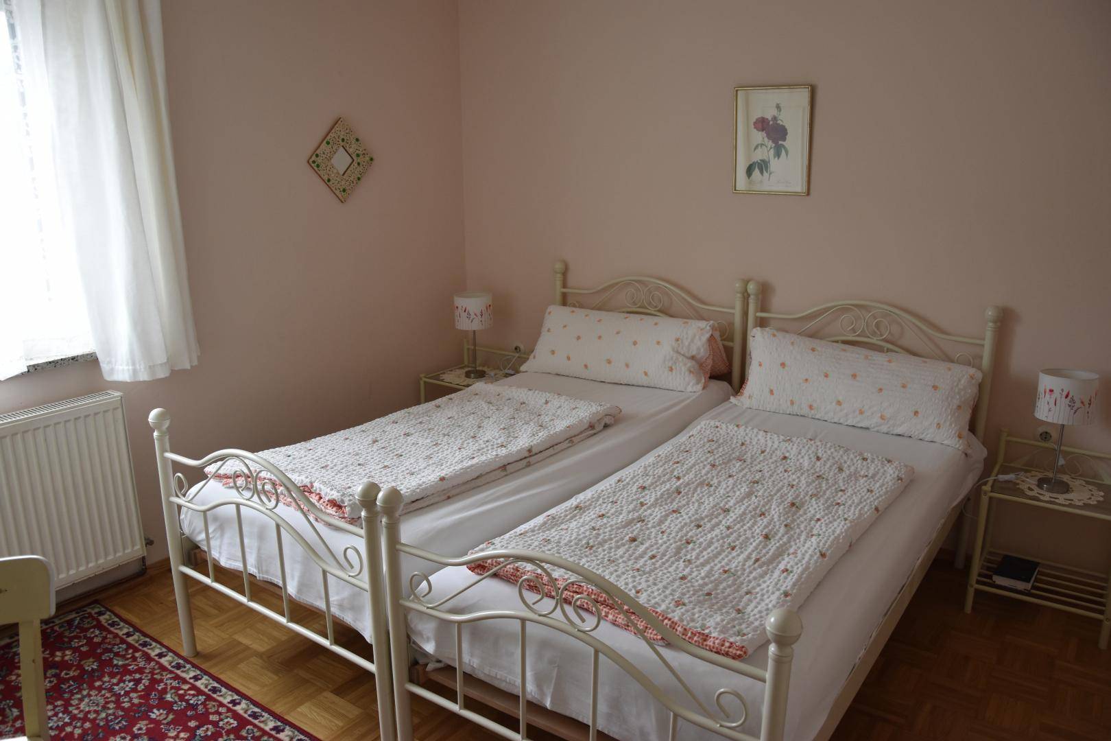 Helles Schlafzimmer mit zwei Einzelbetten im Landhausstil, Nachttischen und einem Teppich, gemütlich eingerichtet.