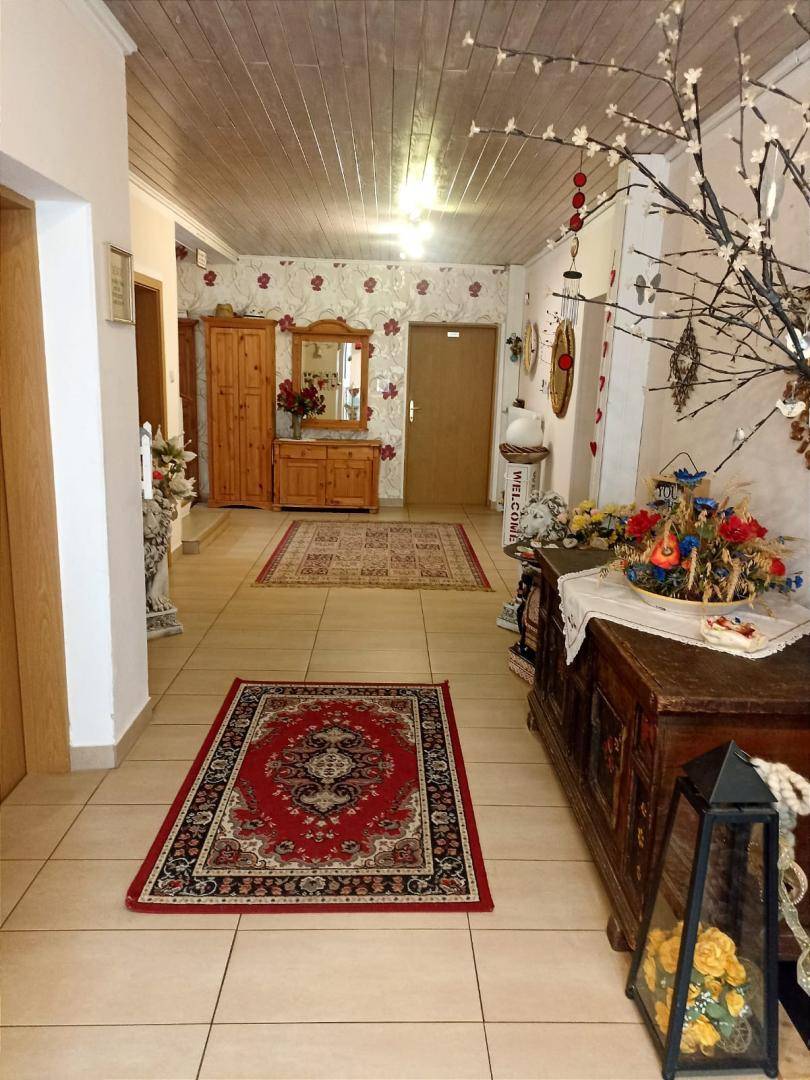 Langer Flur mit Fliesenboden, Teppichen und Holzmöbeln, der zu weiteren Räumen führt, traditionell eingerichtet.