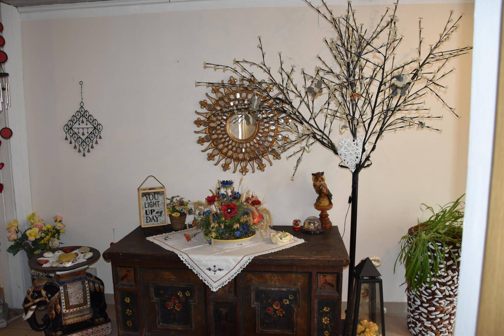 Detailansicht eines Flurbereichs mit rustikaler Kommode, Spiegel und dekorativen Elementen, traditionell gestaltet.