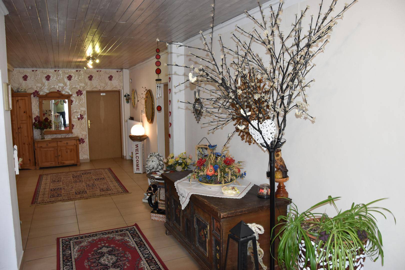 Gemütlicher Eingangsbereich mit Holzdecke, Fliesenboden und traditioneller Dekoration.