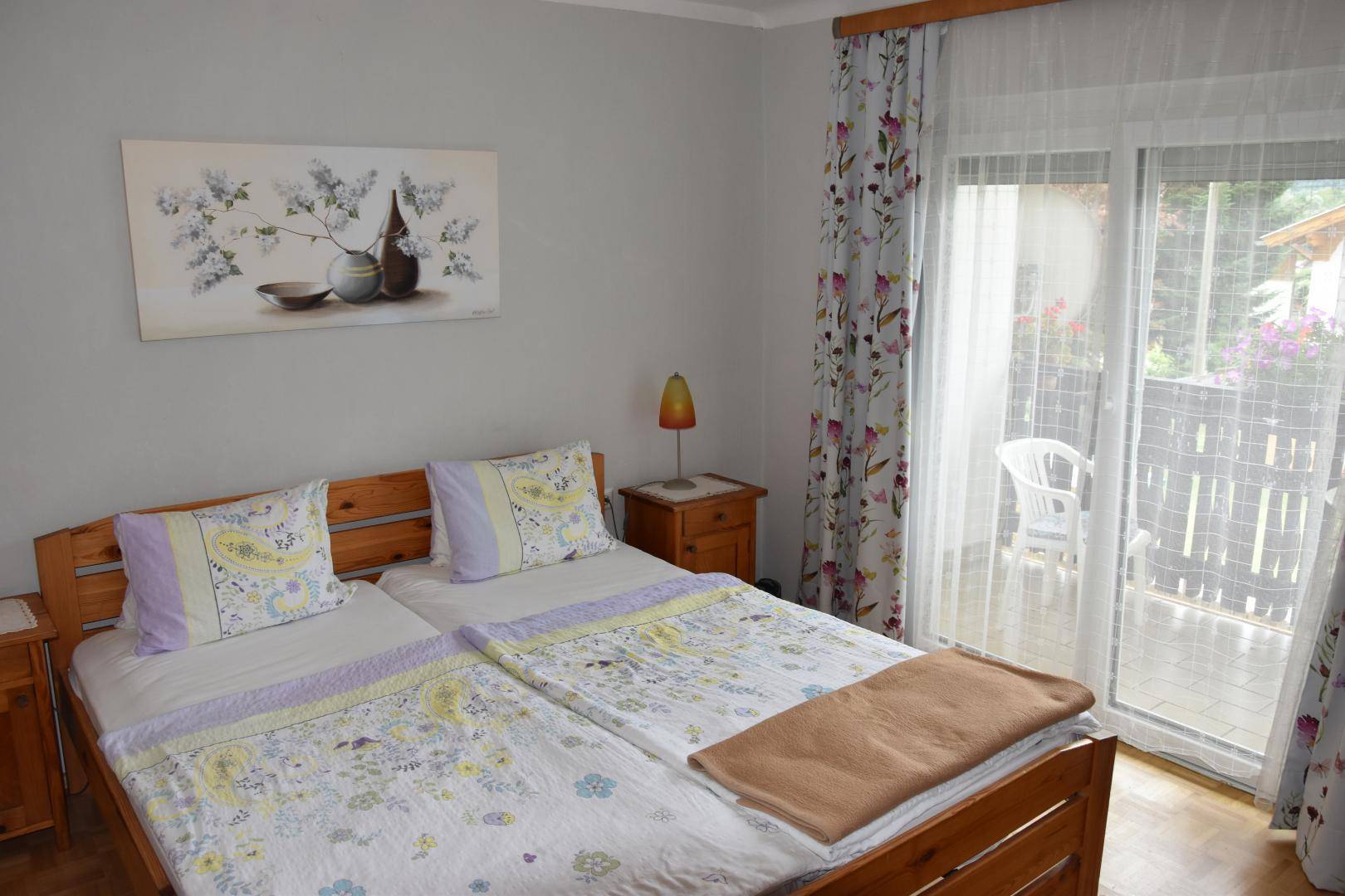 Helles Schlafzimmer mit zwei Einzelbetten, Holzrahmen und Zugang zum Balkon.