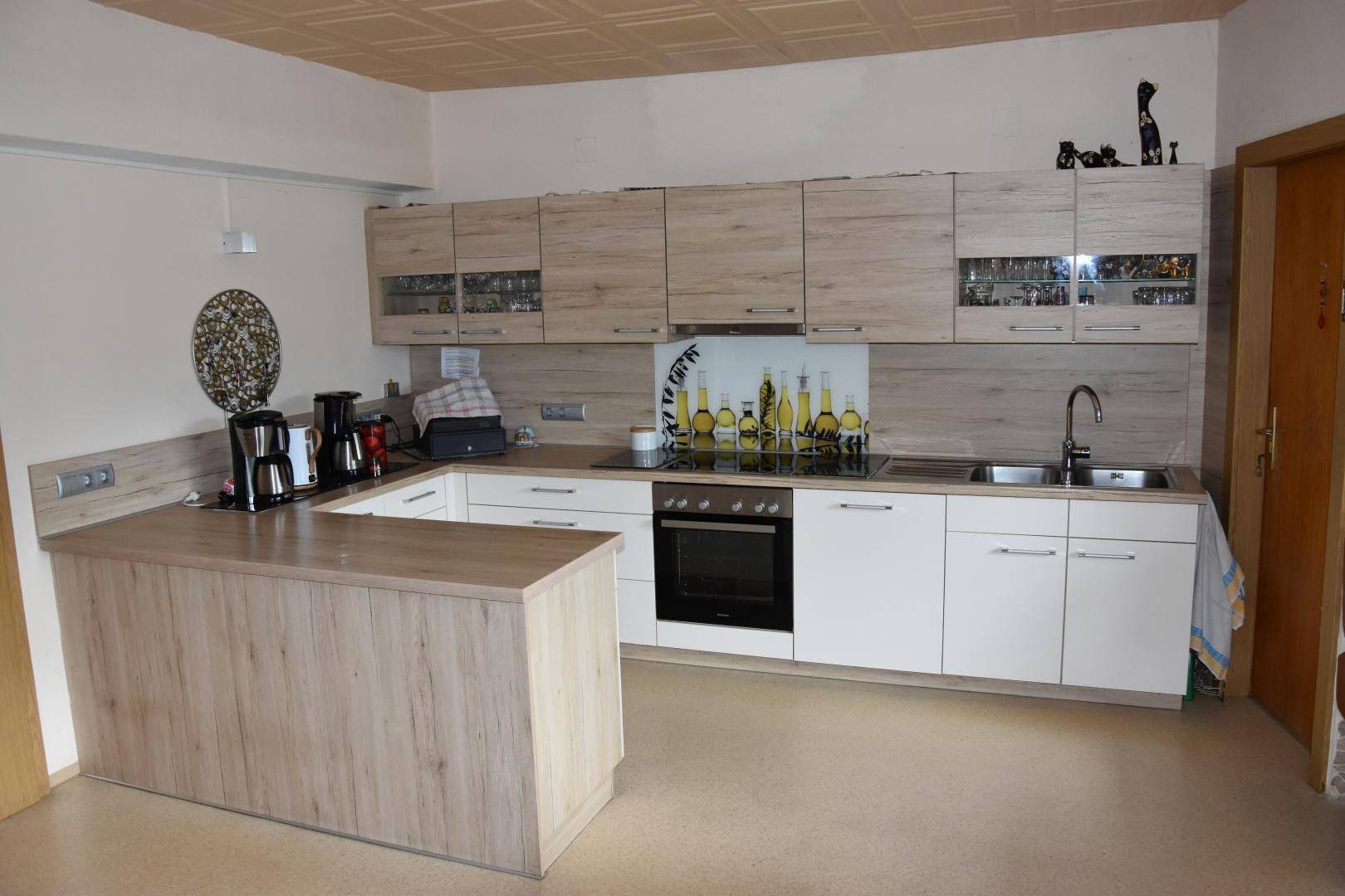 Moderne Küche mit hellen Holzfronten, integrierten Geräten und einer Frühstückstheke.