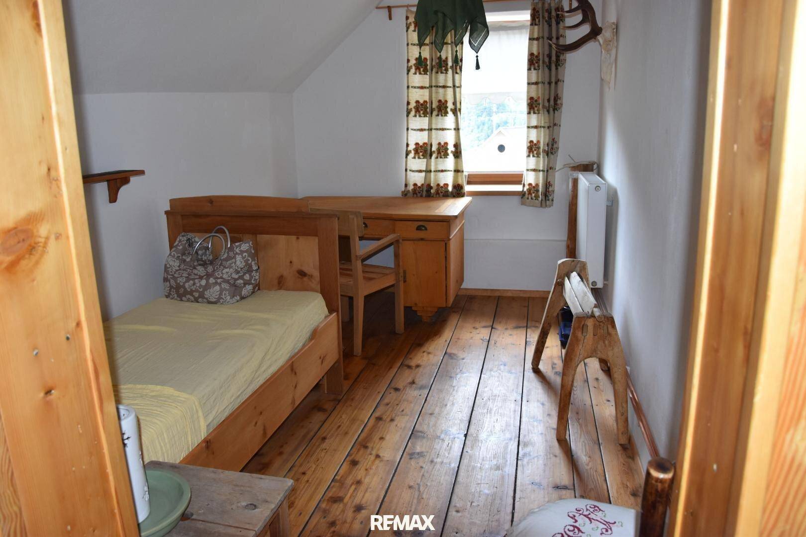 Kleines Schlafzimmer im Dachgeschoss mit Einzelbett, Holzboden und Fenster.