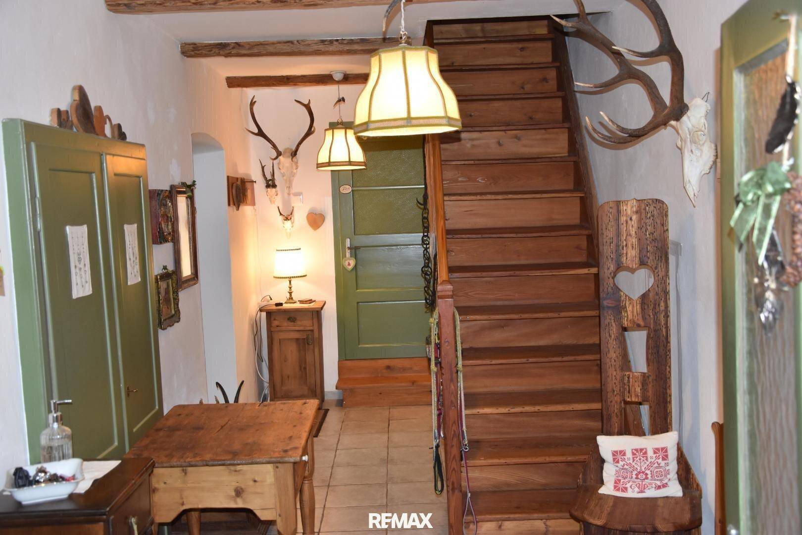 Rustikaler Eingangsbereich mit Holztreppe, Geweihen und traditioneller Einrichtung.