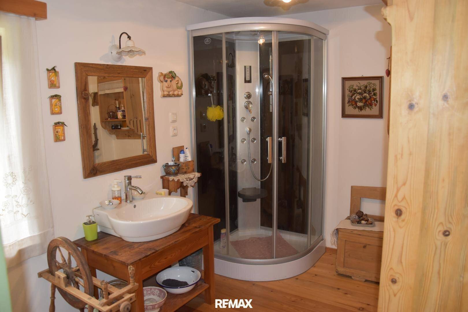 Badezimmer mit Duschkabine, Einzelwaschbecken und rustikalem Holzwaschtisch.