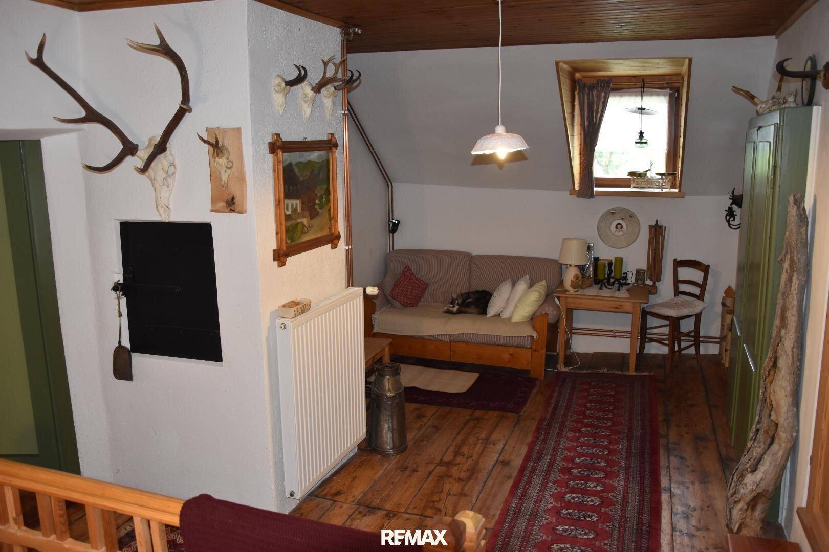 Gemütlicher Wohnbereich im Dachgeschoss mit Holzboden, Sofa und alpiner Dekoration.