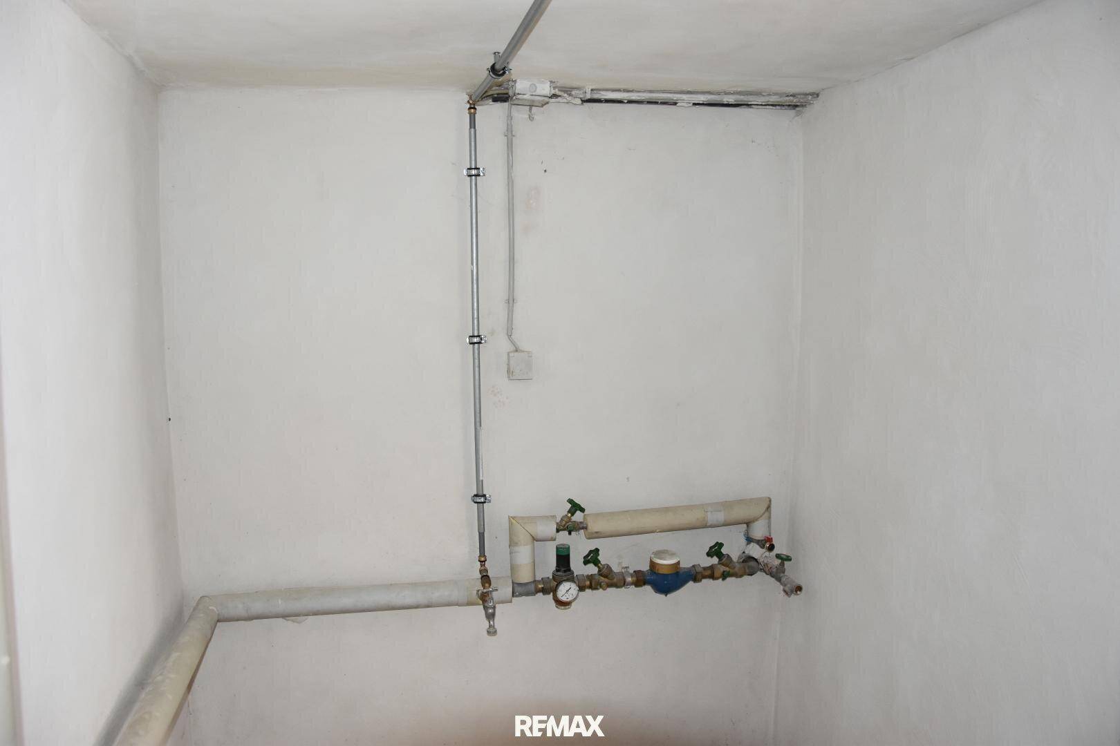 Hauswirtschaftsraum mit sichtbaren Wasserleitungen und Zählern, ideal für technische Installationen.