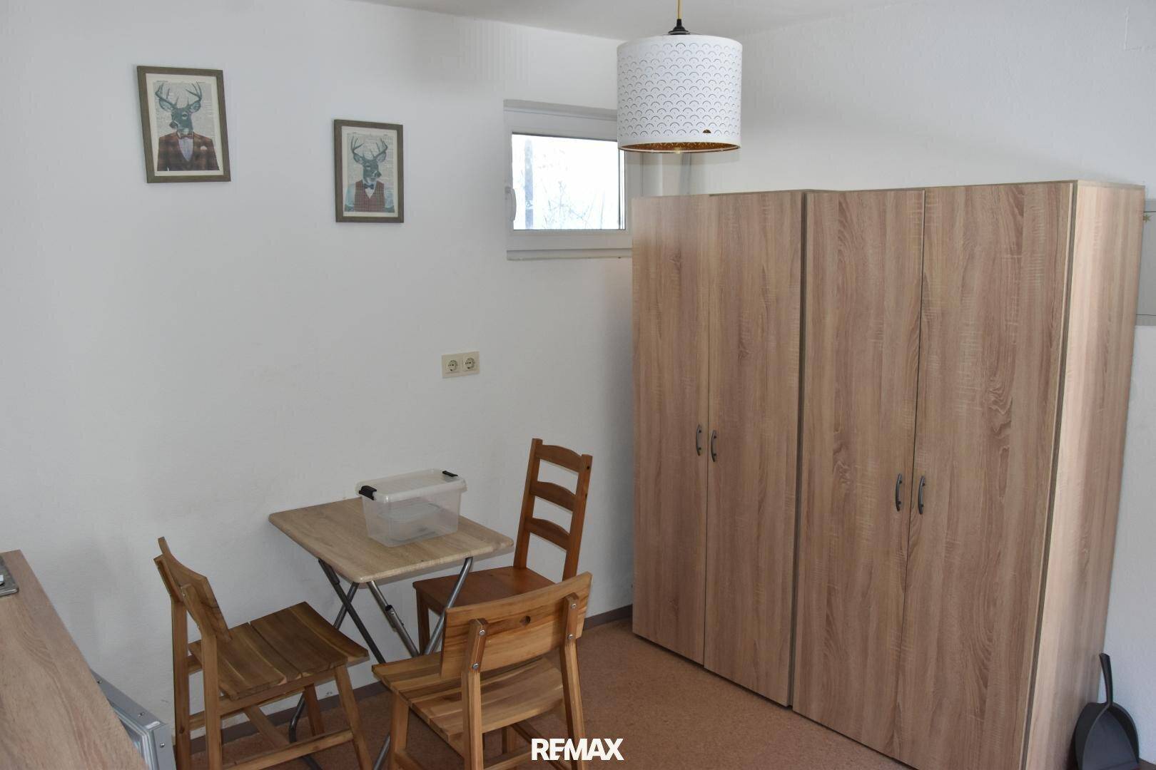 Raum mit einem großen Kleiderschrank, einem kleinen Esstisch und Hirsch-Motiven an der Wand.