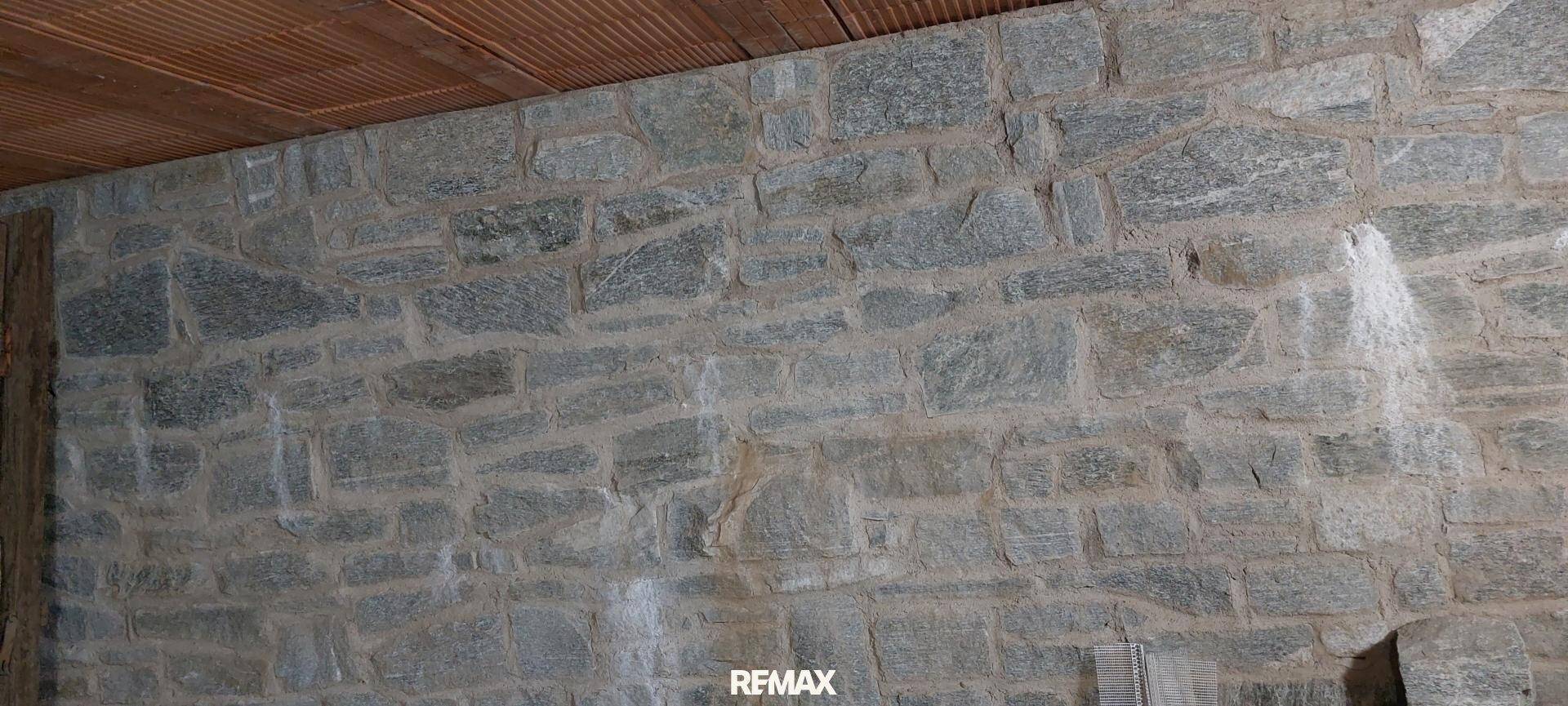 Rustikale Steinwand mit unregelmäßigen Natursteinen, die eine robuste Textur bietet.