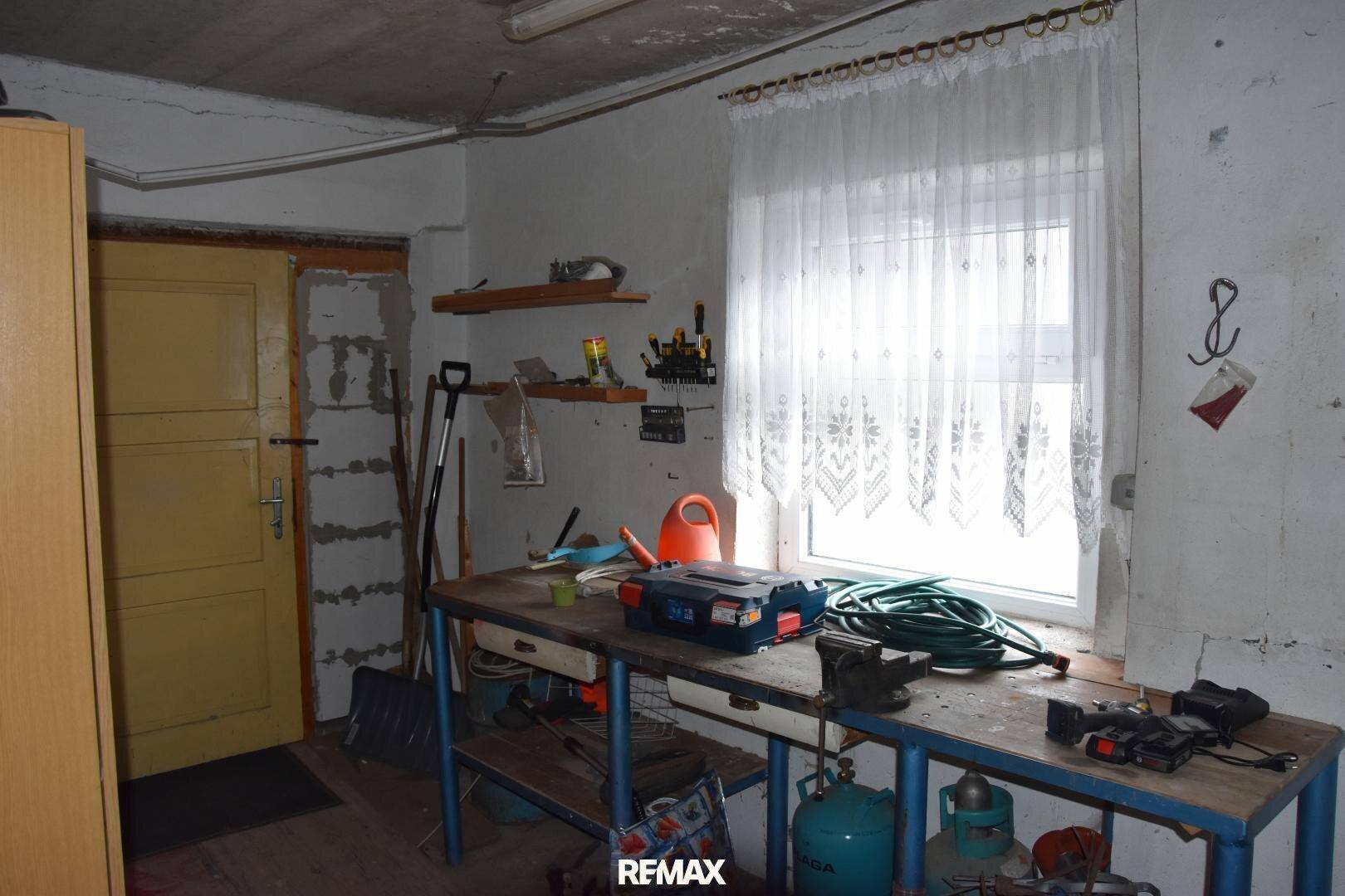 Werkstattraum mit großem Fenster, Werkbank und verschiedenen Werkzeugen.