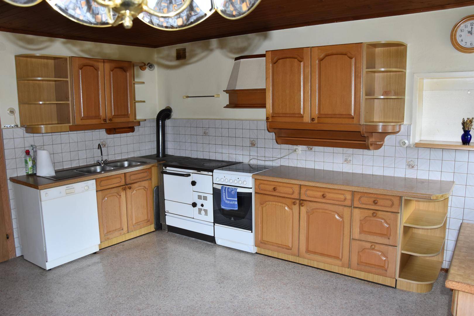 Einbauküche im Landhausstil mit Holzschränken, Spüle, Herd und Geschirrspüler.