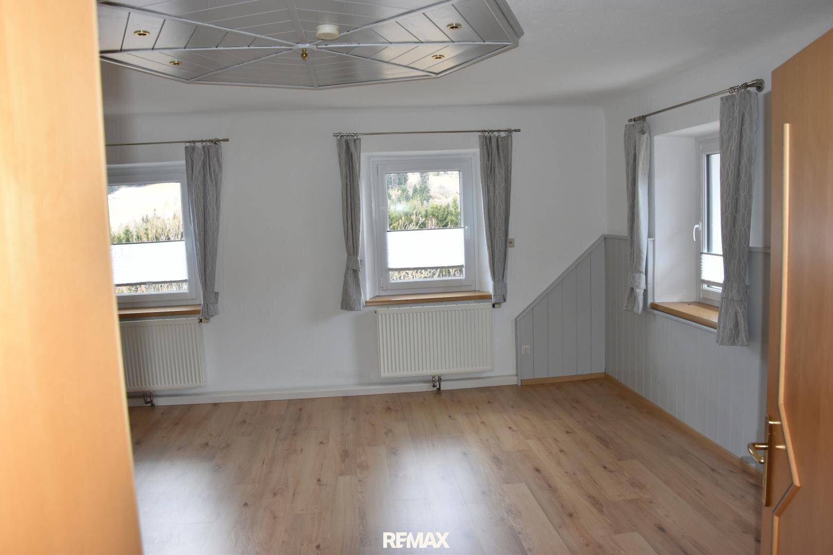 Heller Raum mit Laminatboden und mehreren Fenstern für natürliche Belichtung.