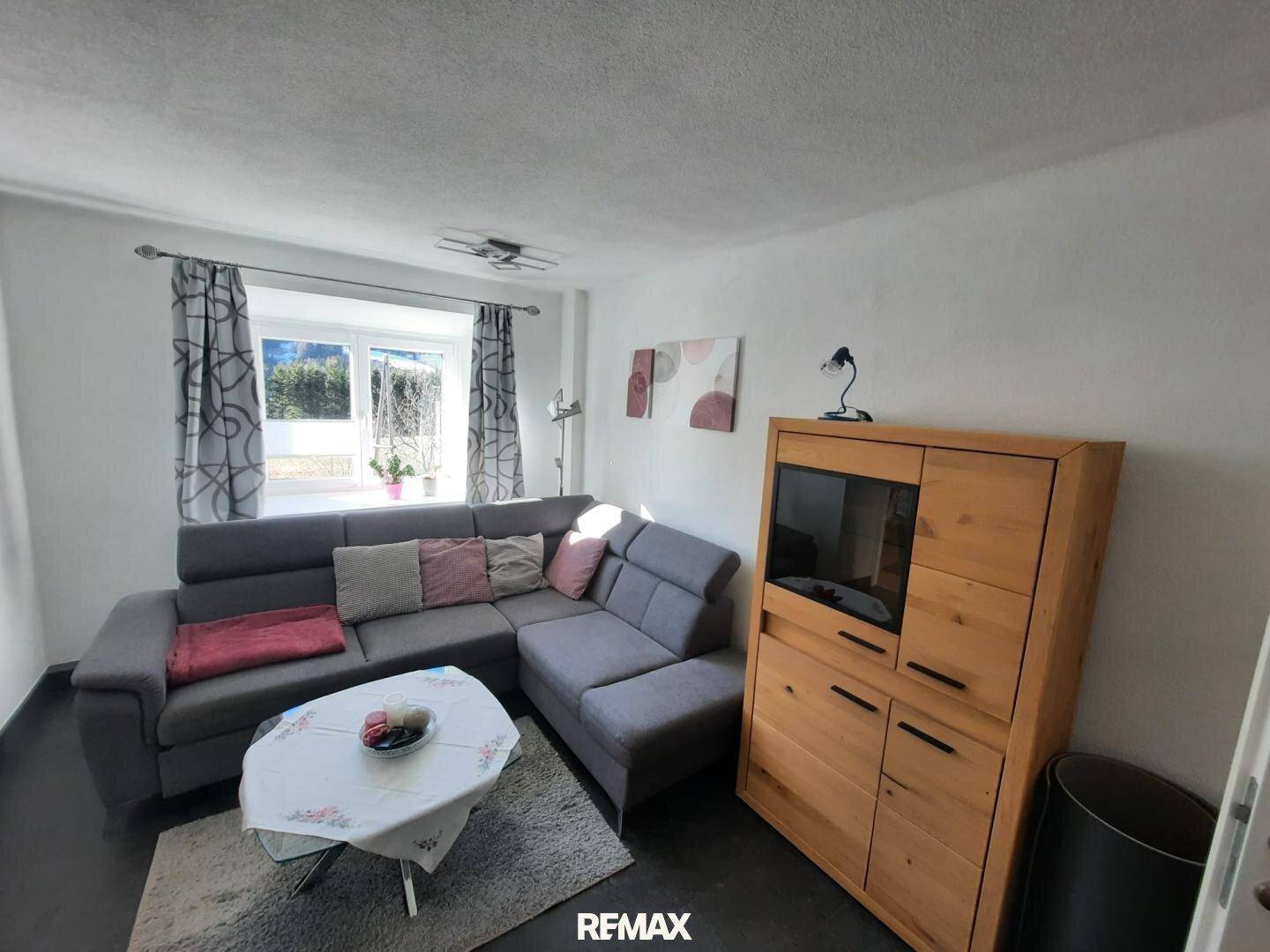 Gemütliches Wohnzimmer mit Ecksofa, Holzelementen und Blick ins Grüne.