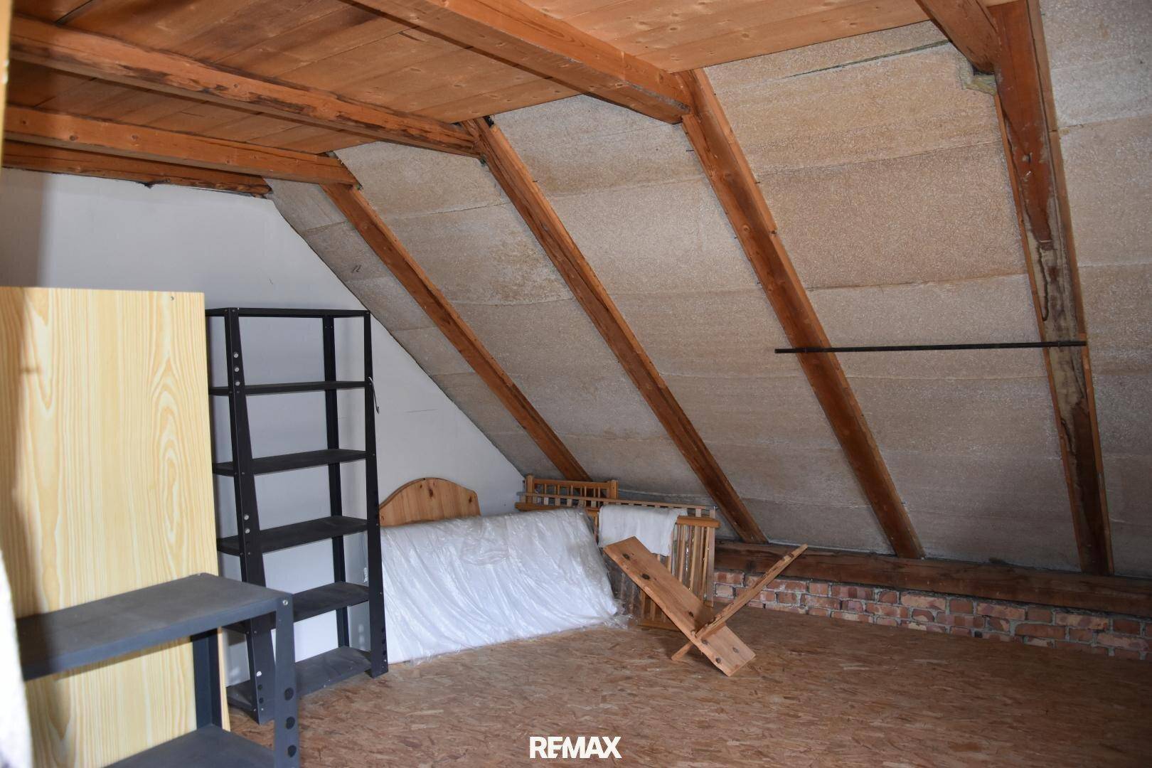 Unfertiger Dachboden mit sichtbaren Holzbalken und Schrägen, ideal als Stauraum.