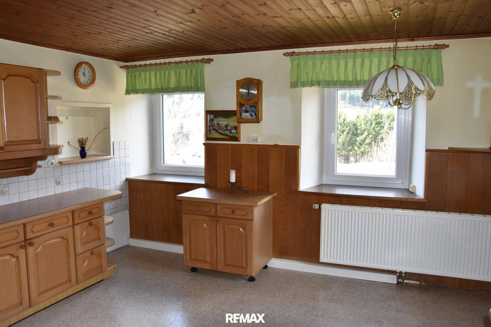 Traditionelle Küche mit Holzschränken, gefliestem Spritzschutz und Blick ins Grüne.