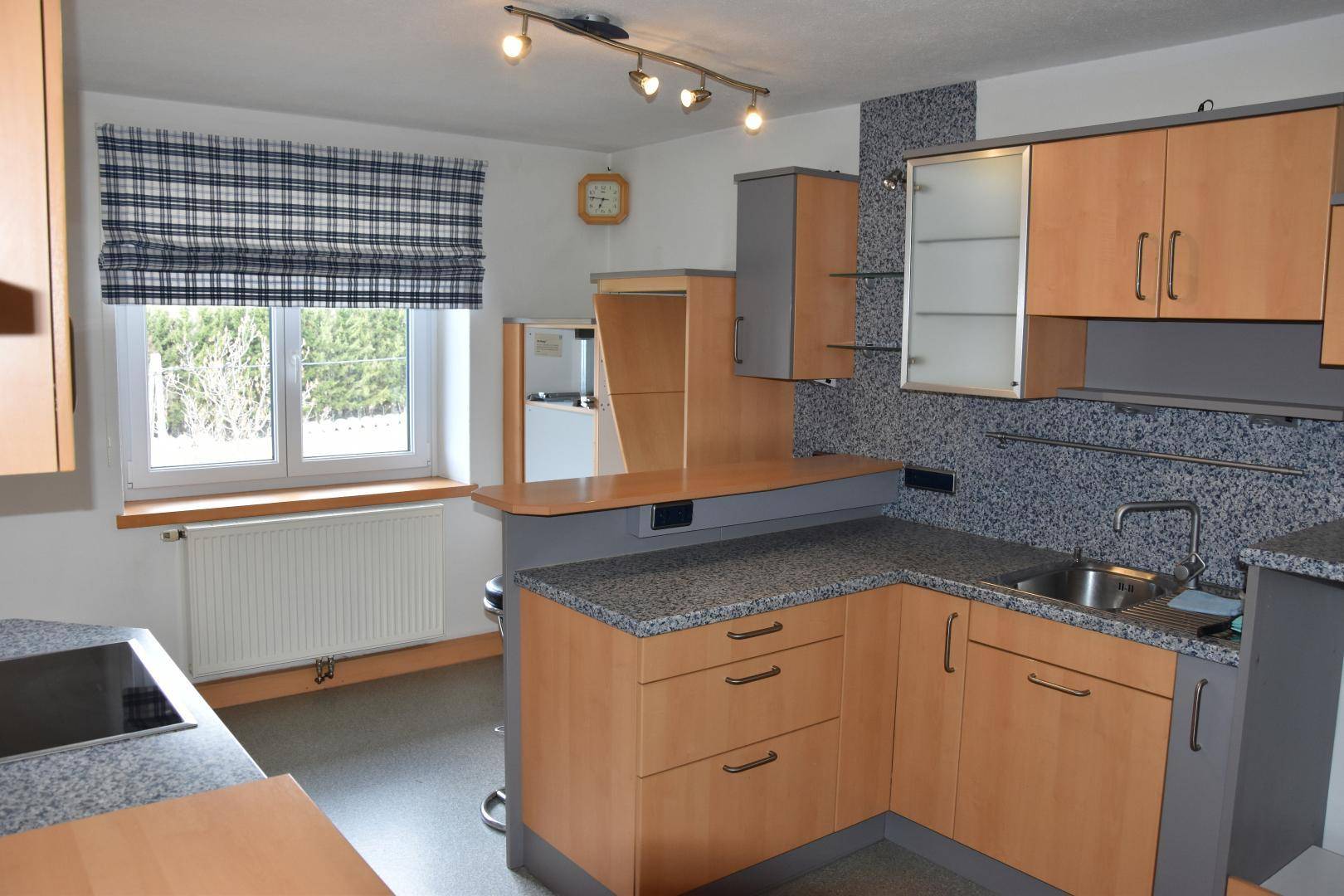 Moderne Einbauküche mit Holzfronten, Granit-Arbeitsplatten und Frühstücksbar.