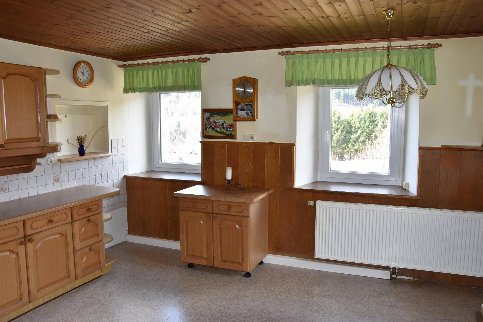 Traditionelle Küche mit Holzmöbeln, gefliestem Spritzschutz und Blick ins Grüne.