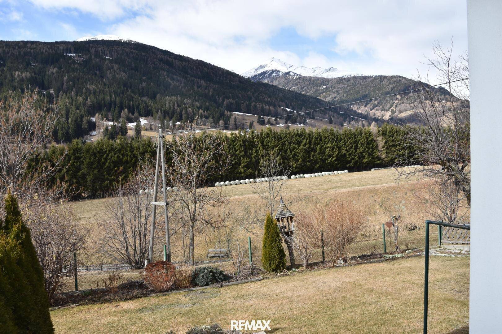 Idyllischer Gartenbereich mit weitem Blick auf die umliegende Berglandschaft und grüne Felder.