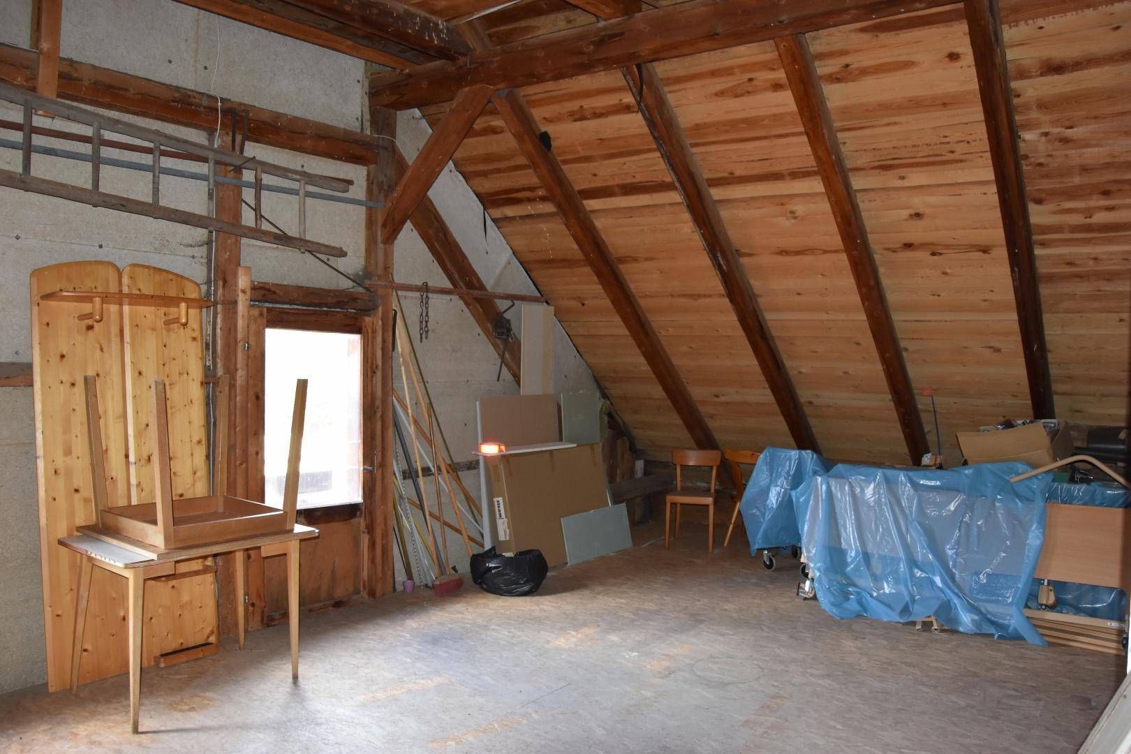 Geräumiger Dachboden mit Holzbalken, Fenster und viel Platz für Lagerung.