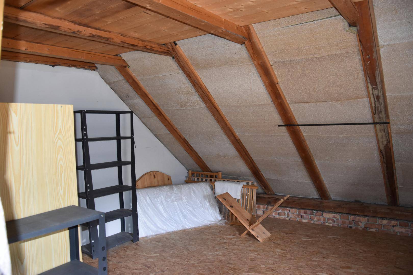 Dachboden mit sichtbaren Holzbalken, schrägen Wänden und Stauraum.